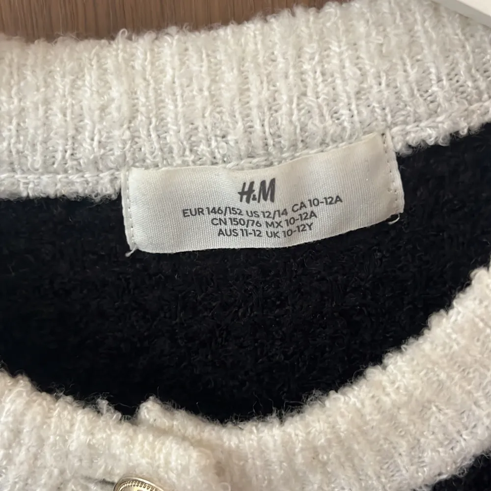 Säljer en snygg svart och vit kofta från H&M. Den har långa ärmar och är dekorerad med fina knappar framtill. Koftan har vita detaljer vid kragen, ärmsluten, fickorna och nederkanten. Perfekt för höst och vinter!. Neuleet.