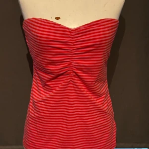 Röd- och vitrandig tubtopp från H&M - Säljer en snygg röd- och vitrandig tubtopp från H&M. Toppen är axelbandslös och har en tight passform. Perfekt för sommaren eller en festlig kväll! 🥳