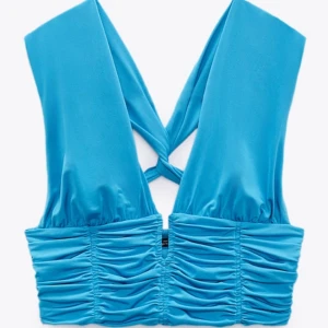 Blå ärmlös topp med rynkdetaljer - Säljer en snygg blå ärmlös topp med rynkdetaljer. Toppen har en unik design med korsade band i ryggen och en tight passform. 💙Perfekt för sommarens fester eller en utekväll med vänner. Materialet känns mjukt och stretchigt, vilket gör den bekväm att 
