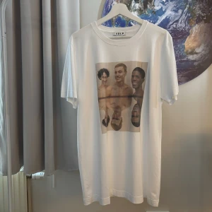 Vit t-shirt från CDLP med tryck - Säljer en vit t-shirt från CDLP x Ruben i storlek M. T-shirten har ett tryck på framsidan från Ruben Östlunds film Triangle of Sadness. Den är kortärmad och gjord av bomull, vilket gör den bekväm och perfekt för vardagsbruk. Passar bra till både jeans och shorts!