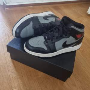 AIR JORDAN 1 MID (gs), unisex. Storlek 37.5 , knappast använd med inga riktiga creases. Svart, grå med ett röd air jordan loga.