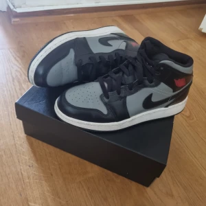 AIR JORDAN 1 MID Grey/Red - AIR JORDAN 1 MID (gs), unisex. Storlek 37.5 , knappast använd med inga riktiga creases. Svart, grå med ett röd air jordan loga.