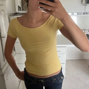 Gul topp från Lindex - Säljer en söt gul topp från Lindex i storlek XS. Toppen är kortärmad och har en tight passform. knappt använd så Inge defekter 