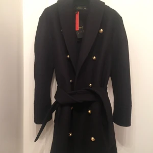 Kappa H&M Balmain - Säljer en jättefin skepparkappa/ullkappa i mörkblått med guldknappar från H&M i samarbete med Balmain som inte kommit till användning. Alla tags/lappar kvar! Nypris 2500kr.