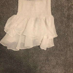 Volang kjol - Säljer en fin vit volangkjol som även kan användas som topp. Säljes då den inte används längre. :)