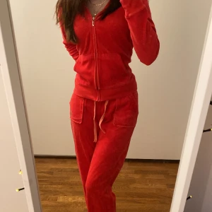 Juicy couture set - Ett rött Juicy couture set med loggan på vänstra benet och ryggen på koftan. Både koftan och byxorna är i storleken Large men dom passar S också.