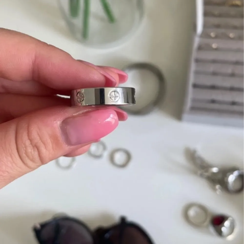 En elegant silverfärgad ring med ingraverade symboler runt om. Ringen har en slät yta och en modern design (liknar cartier love ring). Accessoarer.