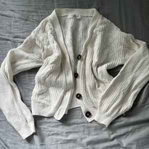 Stickad kofta - Vit stickad kofta med bruna knappar. Köpt på barnavdelningen men funkar för mig som vanligtvis använder S. 