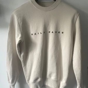 Beige tröja från Daily Paper - En beige tröja från Daily Paper. Tröjan har långa ärmar och ribbstickade muddar vid ärmslut, nederkant och halsringning. Helt nytt skick, nypris 1099kr