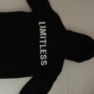 En svart hoodie med texten 'LIMITLESS' tryckt i vitt på framsidan. Hoodien har en luva med dragsko och långa ärmar. säljer på grund av storlek men passa för både L och M 