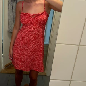 Blommig klänning - Röd klänning med vita små blommor. Jätte fin gullig klänning. Använd fåtal gånger så varsamt använd och i fint skick. 