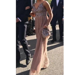 Rosa/Beige balklänning med väska - Rosa/Beige balklänning, från Maya, säljs med tillhörande väska. Smala band, v-ringad, paljetter upptill och kjolen är i mesh. Använd en gång, mindre slitage (skickar fler bilder vid intresse). 