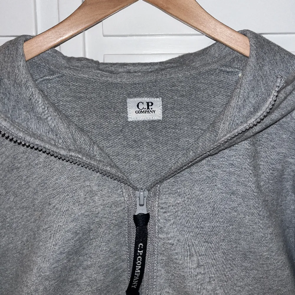 Grå zip hoodie från CP Company i storlek M. Hoodien är så gott som ny och är endast använd ett fåtal gånger. 10/10 skick. Pris kan diskuteras och tveka inte på att höra av dig vid andra frågor.  Nypris: 2700kr. Hoodies.