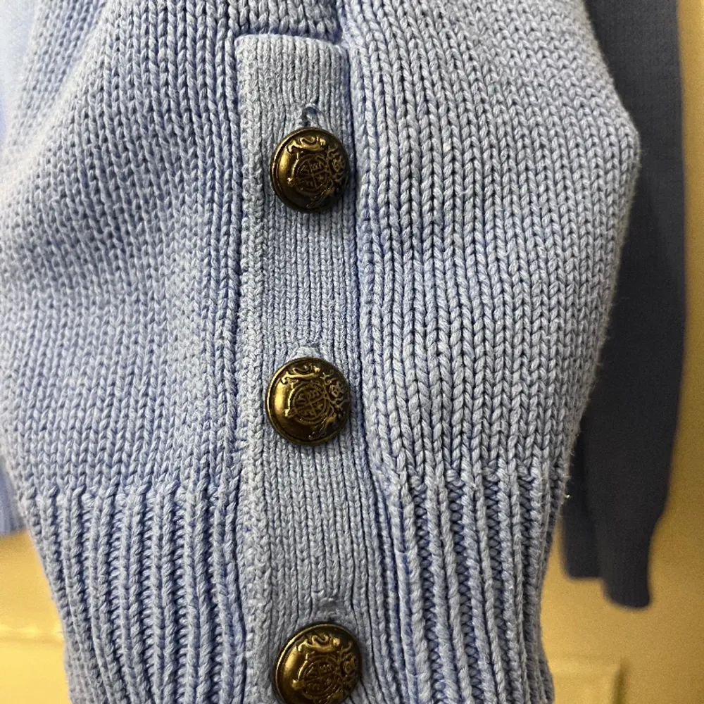 Blå stickad tröja med knappar vid sidan. Hoodies.