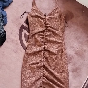 Bronze festklänning! - En oanvänd bronze festklänning! Använd en gång på nyår, passar nog till de mesta, ganska kort beroende på längd. Stretchig, frakt kostar inte och den är ren. Från Divided:)) Pris kan diskuteras