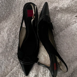Kitten-heels klackar med rosett - Spetsiga klackar från Coach i äkta läder med rosett vid tårna. Superfina och i otrolig kvalité med söm-detaljer runt sulan och tån. Väl använda med några defekter vid klacken, men inget som syns på långt håll. Passar mig som har 38-39, kan justeras.