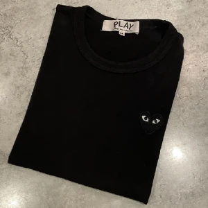CDG T-shirt - Det är en t-shirt från Comme des Garçons PLAY i färgen svart. Storleken är i M men det stämmer inte överens med den verkliga passformen. Jag skulle säga att den är i storleken XS/S. 