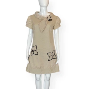 Klänning - Klänning från Wasabi, en av blommorna saknar en knapp. Står ingen storlek. Dockan använder storlek XS. Finns ingen underkjol. MÅTT: Axel till axel 40cm, Ärmlängd 18cm, Armhåla till armhåla 48cm, Midjebredd cirka 40cm & Längd (från armhåla och ner) 68