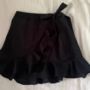 Svart kortkjol strl XS - Svart gullig kortkjol från Shein i strl XS, har resår och knyte så passar S också. Sparsamt använd. 🌸