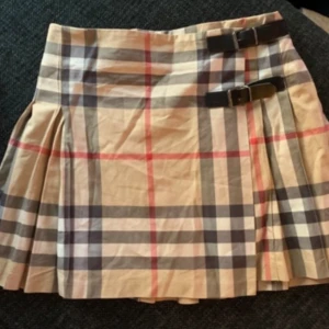 Burberry kjol st 10Y 138 / modell utgått - Denna super klassiska kjol från Burberry i Nova Check. I absolut nyskick. St 10Y/138. Läder spännen så mer utrymme för att ha längre. Går även att flytta knappen på insidan och att ha längre. St 138 dotter mellan 134-152. Pris ny 2900:- minst. Utgått