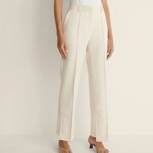 Kostymbyxor med sidoslits  - Beiga/krämvita kostymbyxor med en fin sidoslits. Använd fåtal gånger! Nypris 400kr