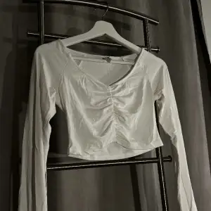 En vit långarmad croppad vit tröja från Nelly i storlek S. Tunn men inte genomskinlig.
