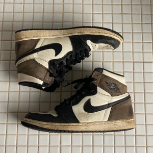 Air Jordan 1 Retro High OG ‘Dark Mocha’ storlek 41 - Höga Air Jordans 1 i mocha, storlek 41. Använt skick och lite smutsiga, men fortfarande fina. Köptes för 5500kr. PRIS KAN DISKUTERAS!💕