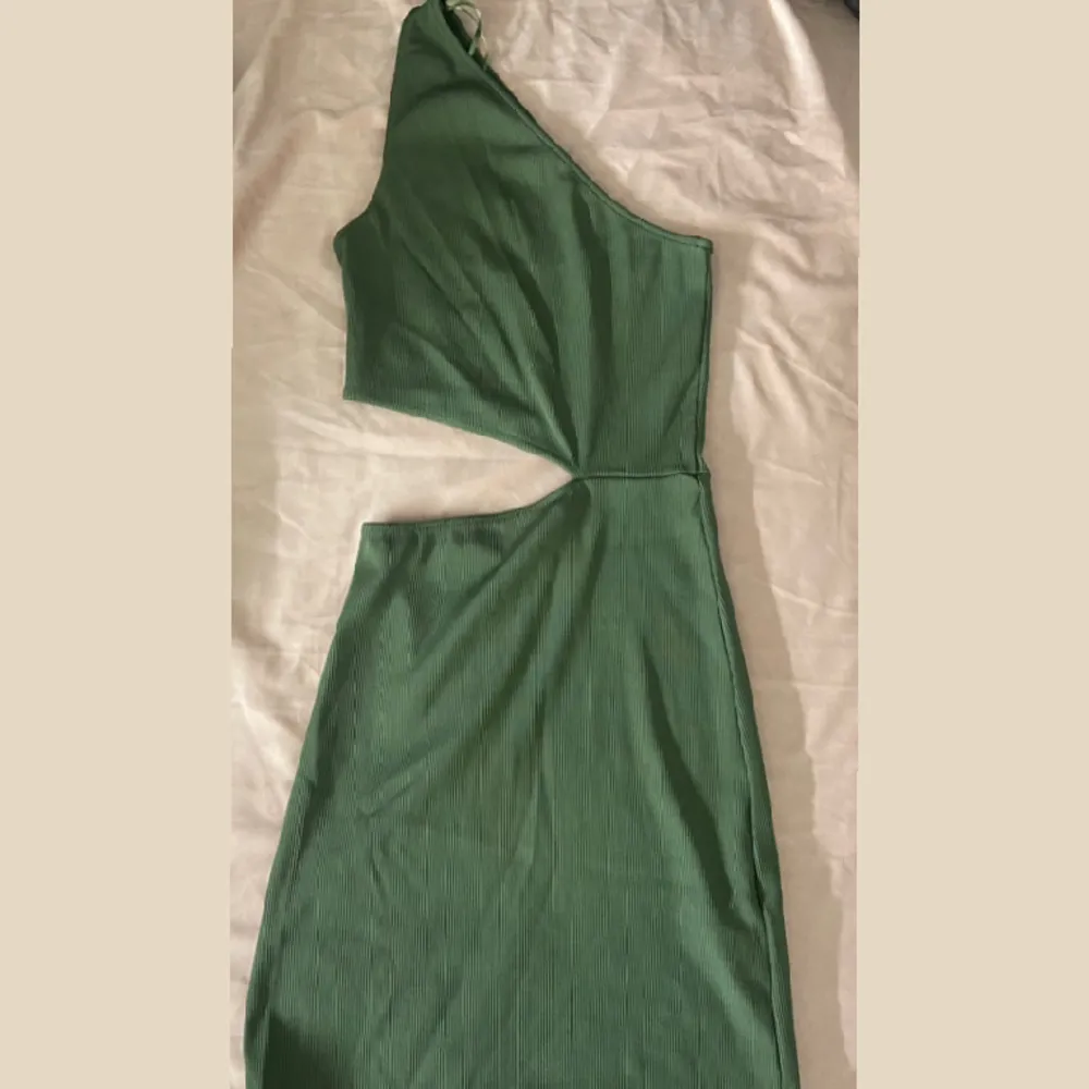 Säljer denna fina one shoulder ribbade gröna klänningen med en öppning på högra sidan. Storlek xs. Från pull and bear använd 1 gång. . Klänningar.