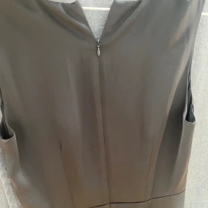 Glansig svart klänning  - Tight passform med v-hals och volang nertill. 