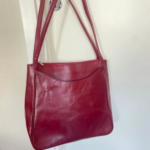 Röd axelremsväska - Röd skinnväska. 30x30x10 cm.   Har ett litet märke på baksidan, se bilder☺️