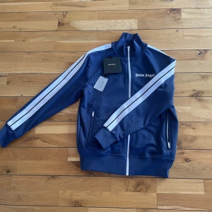 Palm angels track zip jacket - Köpt för något år sedan fortfarande i Väldigt bra skick, sparsamt använd. Liten i storlek så om du brukar ha M passar L perfekt