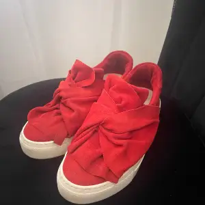 Säljer nu dessa fina röda sneakers som inte kommer till användning längre. Skorna är i bra skick. Frakt kan tillkomma.  Detalj: Knut ovanpå som de ut som en rosett.   Storlek: 37  