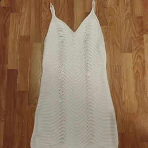 Vitstickad kortklänning - Vit garnstickad kortklänning med fint design och slits på båda sidor,stl M