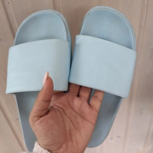 Tofflor/Sandaler/badtofflor med platå,40/41,H&M - Ett par badtofflor med bred rem i läderimitation och platå. Formgjuten sula som har räfflad undersida. Sulhöjd 4 cm.I mycket fint skick, behöver rengöras från smuts vg och se bilder  Storlek 40/41  Färgen ljus turkos/Enfärgad 