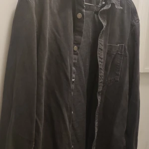 Jeans skjorta- jacka i svart denim Stl M - Jeans skjorta- jacka i svart denim Stl M  Bra skick använd väldigt få gånger