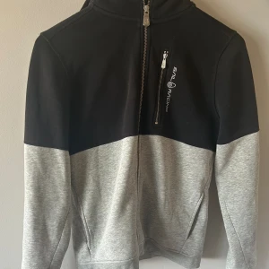 Sailracing ziphoodie - Jag säljer min sailracing ziphoodie då den är för liten för mig. Den är gråsvart och storlek 170. Nypris: 1299, mitt pris: 499. Skick: 7/10. Kan sänka till 449 vid snabb affär. Inte för varm, passar till sommarkvällar.  tar byten.