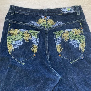 Baggy dadasupreme jeans - Sjuka baggy jeans från hiphop märket dadasupreme i storlek 36 därav rätt långa. Jättemånga feta detaljer och inga defekter.  DMa om frågor eller fler bilder. Mått: midja 45cm, längd 114cm, lår 38cm, benöppning 25 cm.