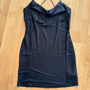 Svart miniklänning i satin - Väldigt fin svart miniklänning i satin 🖤 Med spaghetti snörning som korsar i ryggen    Längden är väldigt kort