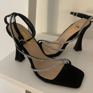 Elegant kvinnor sandaler  - Kristall klackar med bälte och med svart mockamaterial till. Klackarna är helt nya, aldrig använts och mycket bekväm klack. 