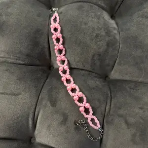 Handgjort pärlarmband i rosa pärlor med silvrigt spänne i gulligt mönster. Justerbar passform mellan 20-26 cm.