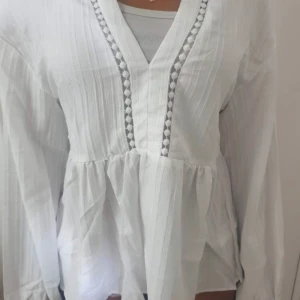 Vit blus - Snyggt mönster vid v-ringningen och den är använd endast en gång. 