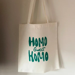 Tygkasse, tygväska, tygpåse  - Handsydd tygkasse med motivet ”homo sweet homo”.   Tillverkad i 100% återvunna textilier. Motivet är handmålad med textilfärg.   Mått: 32x35 cm  Hämtas på Södermalm alternativt skickas med post. 