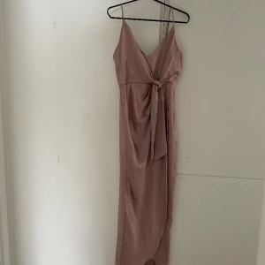 Balklänning  - Endast provad klänning, säljs då den är för liten för mig. Fin rosa klänning med slits och knyte fram:) Skickar gärna bild fler bilder