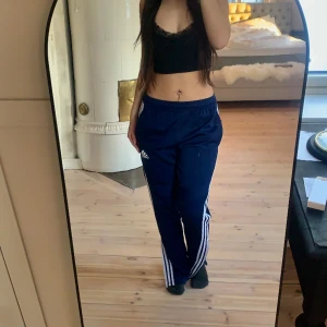 Blåa Adidas byxor - Nästan aldrig använd och fortfarande bra kvalité. Går även att dra ner kedjan vid fötterna så byxorna sätter sig tightare vid smalbenen. 