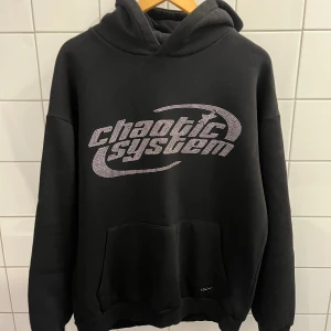Svart rhinestone hoddie - En svart rhinestone hoddie i storlek M. Produkten är i relaxed fit. Har knappt haft denna i ett år och tvingas nu sälja den då den inte passar. Riktigt cool och snygg.