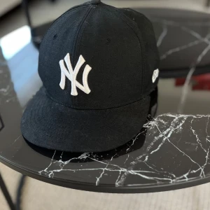 New era keps  - En new era keps med New York yankees. Väldigt fint skick. Justerbar så passar alla. Ett pytte litet märke som kan sys på sidan. Men det är inte märkbart så inget man tänker på. Se andra bilden. Därav ett billigt pris. Förövrigt kanon skick! 