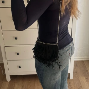 MINI VÄSKA MED FRANSAR💌 - Jättesnygg väska med fransar!! Väskan har tyvärr lite märken såsom att fransarna spretar lite och dragkedjan har gått sönder lite annars är den i bra sick.(jag kan fixa dragkedjan vid intresse)Dragkedjan är silvrig och rostar inte❣️