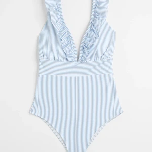 Randig baddräkt (ny) - En jättefin baddräkt med volanger 💙 Oanvänd, bara testat (med underkläder såklart). Prislappen är kvar och det lilla hygien-skyddet. Är för liten för mig och har därför inte kommit till  användning 💞 Jättebra skick! Original pris: 299 kr