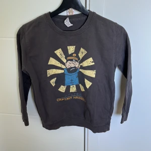 Tröja - Cool tröja med tryck av ”captian hook” från tin tin, storleken är oklar men passar ungefär på 8-11 åringar