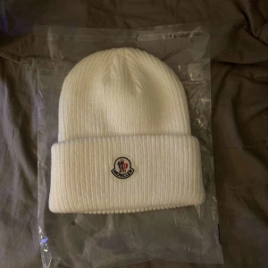Moncler mössa - Säljer moncler mössa vit som endast är använd väldigt lite nu på vintern och som inte kommer användas längre